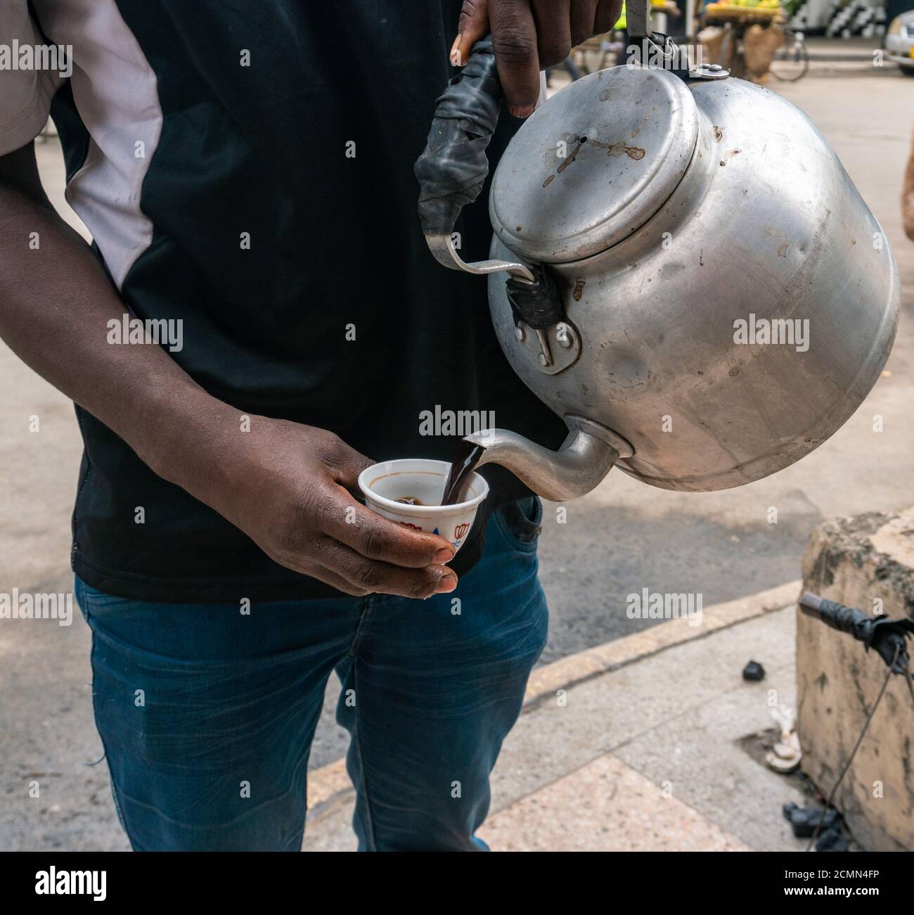 Black African Man versare il caffè in una piccola tazza Pial per strada a Dar es Salaam, Tanzania, Africa Foto Stock