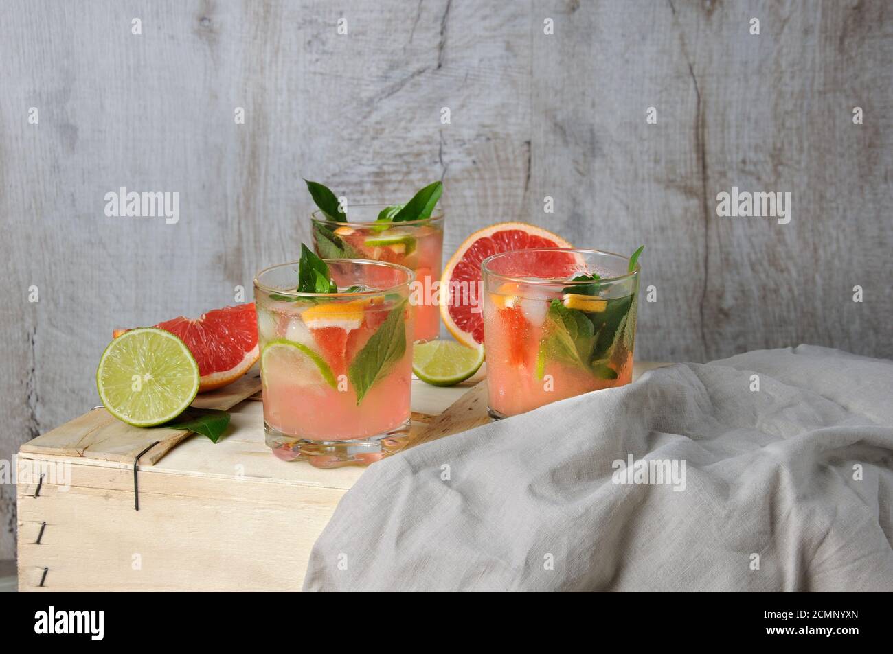 Cocktail di succo di pompelmo rosso spremuto e foglie di limone basilico delicato, fette di lime e peperoncino Foto Stock