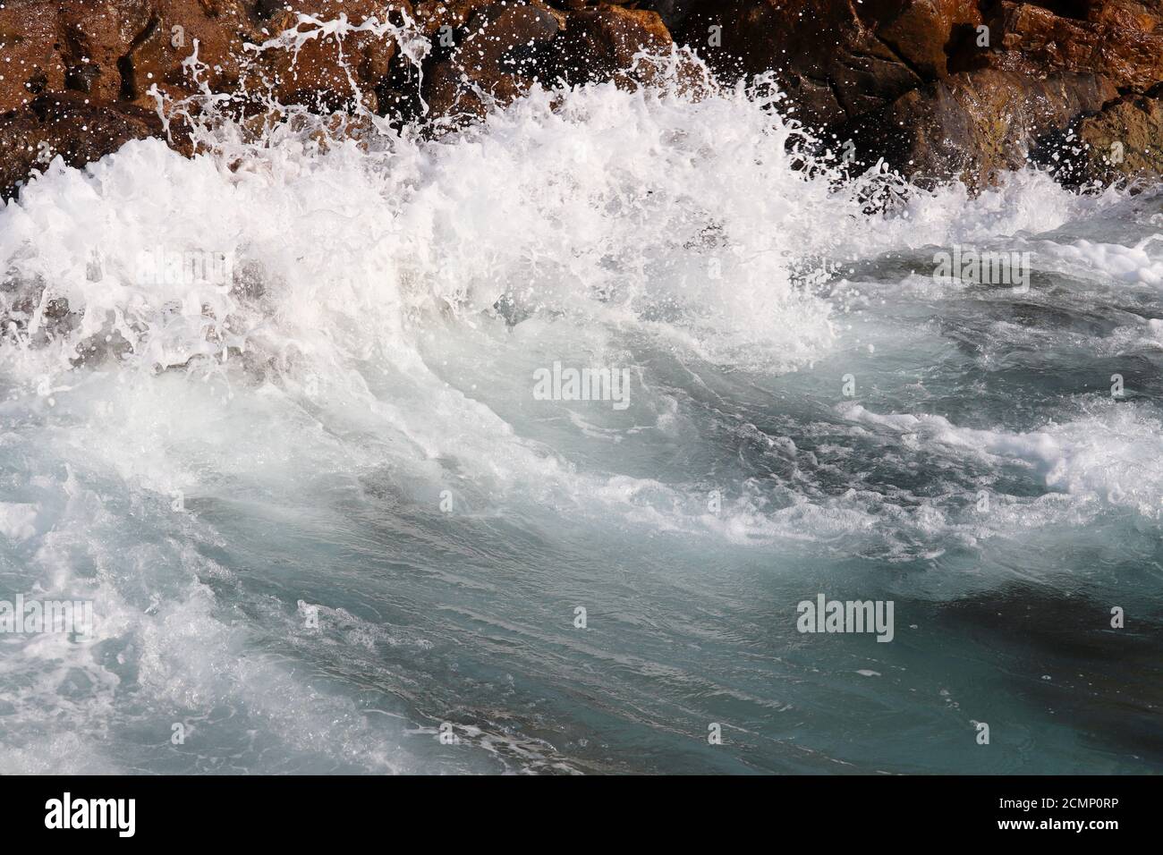 Le onde si infrangono sulle rocce sul mare. Acqua schiumosa pulita su pietre, tempesta di mare Foto Stock