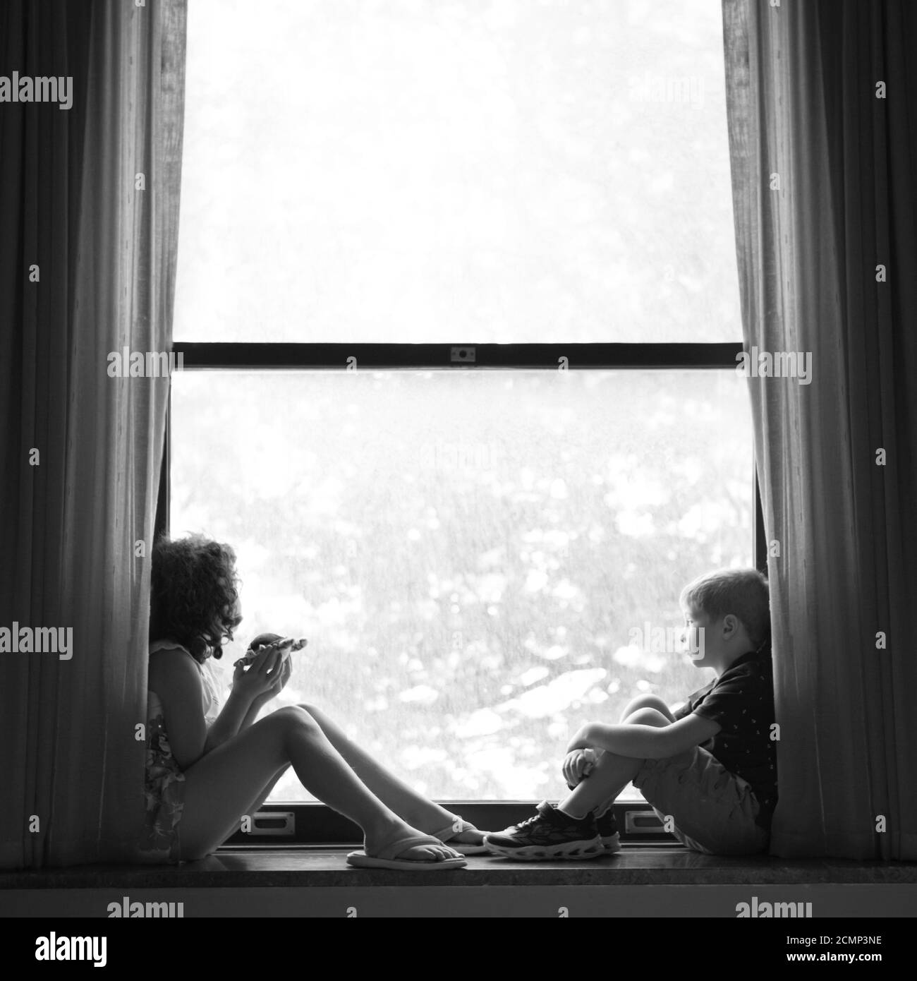 Un ragazzo e una ragazza siedono all'interno di una grande finestra retroilluminata Foto Stock