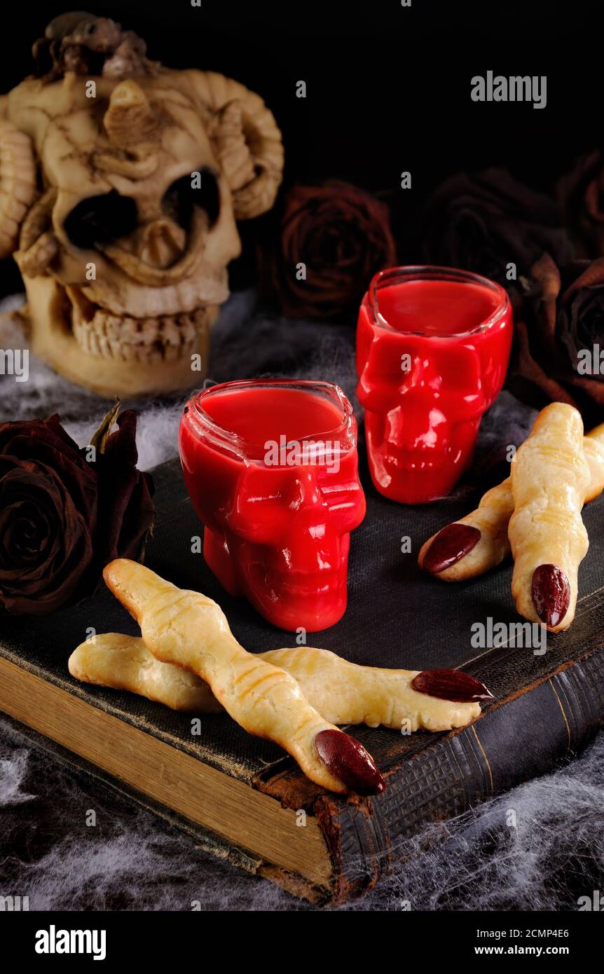 Immergere i biscotti croccanti con shortbread sotto forma di dita di strega In velluto rosso di cioccolato caldo. Questo è jus Foto Stock