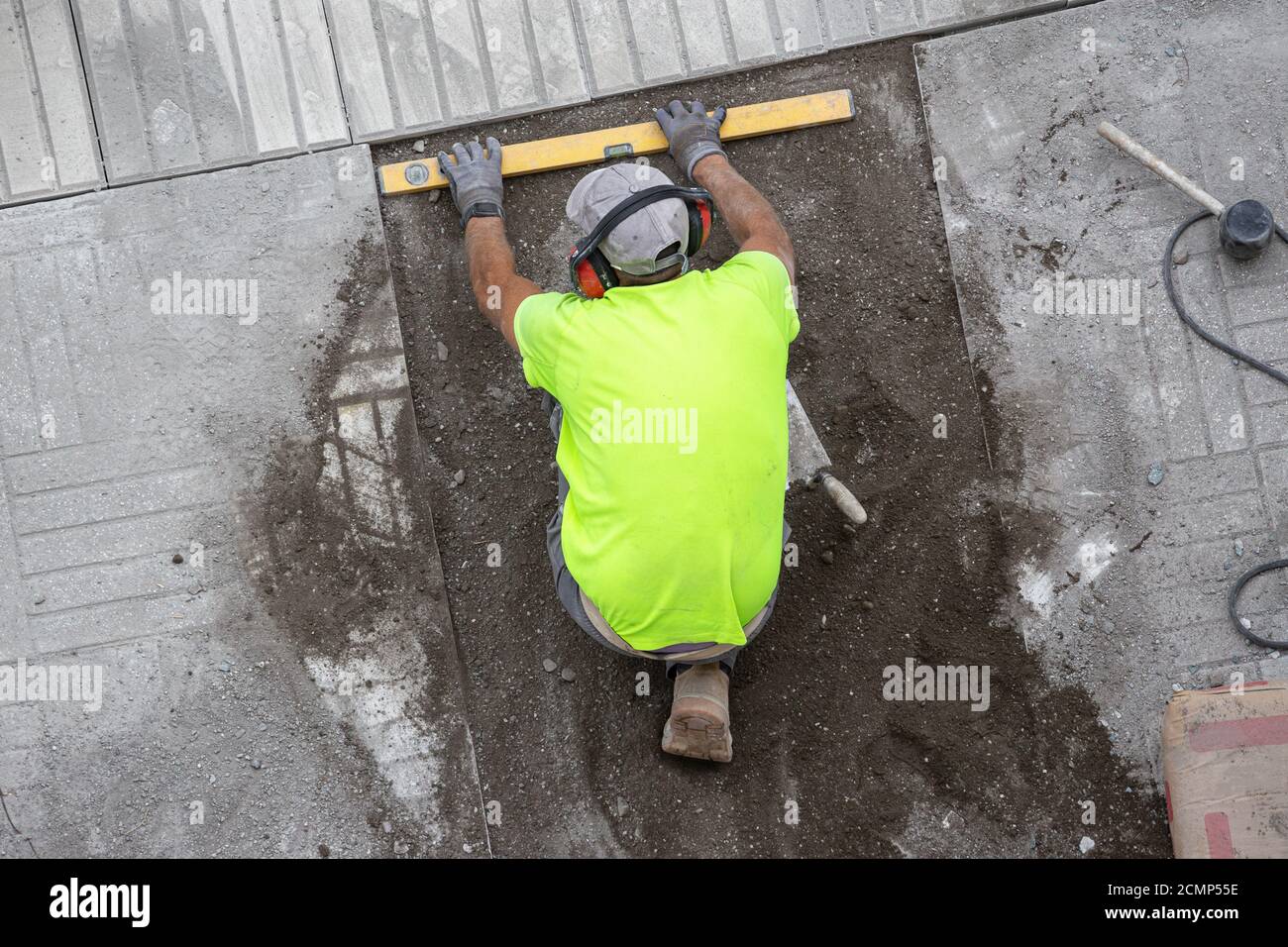 Lavoratore di costruzione con piano di costruzione che lavora su un marciapiede. Concetto di manutenzione Foto Stock