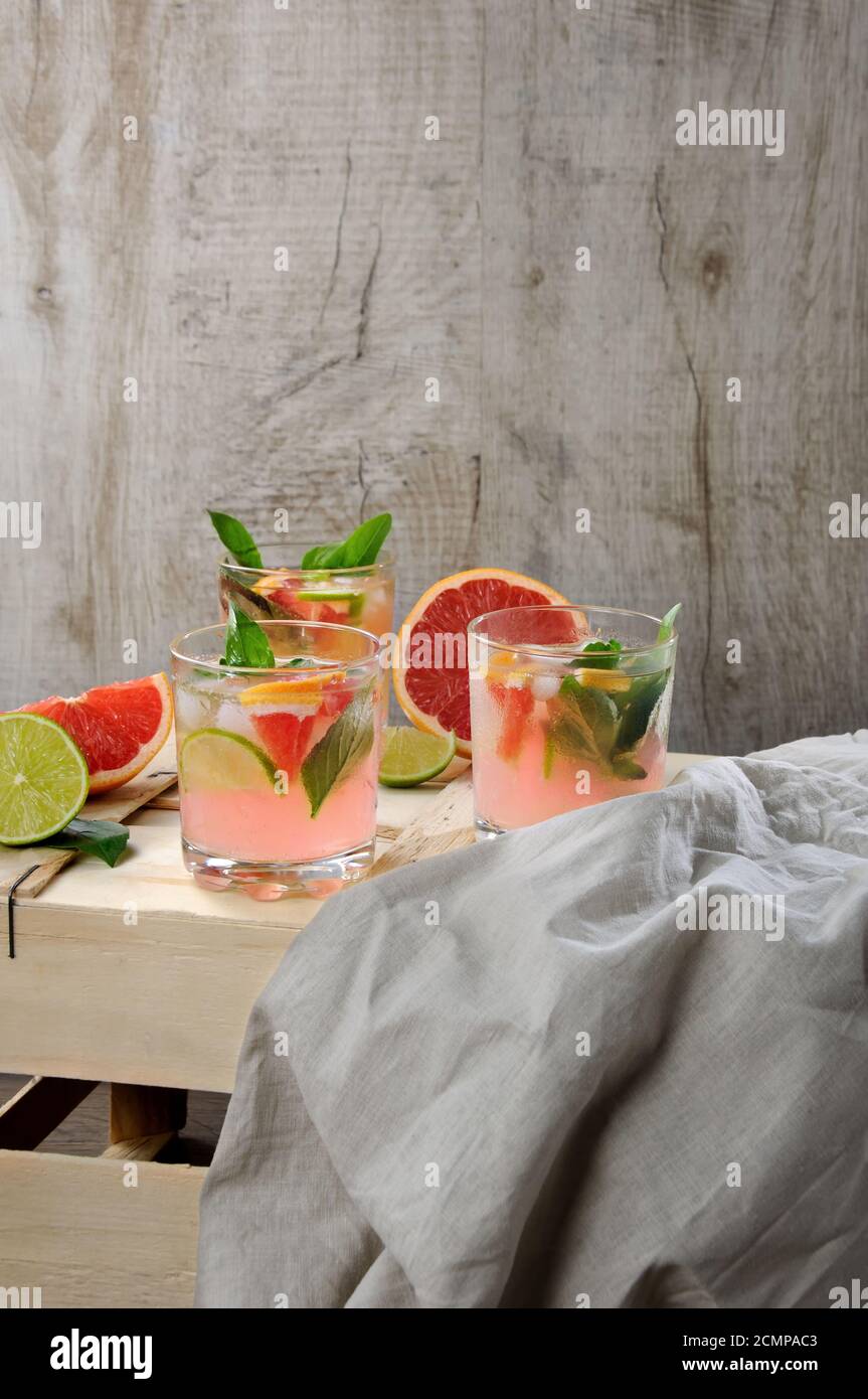 Cocktail di succo di pompelmo rosso spremuto e foglie di limone basilico delicato, fette di lime e peperoncino Foto Stock