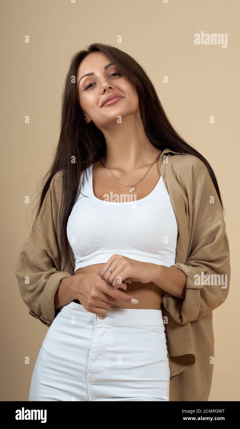 Ritratto di giovane donna allegra che indossa abiti casual su beige sfondo Foto Stock