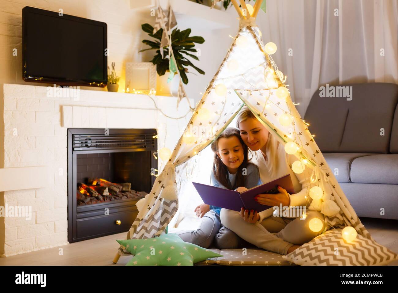 madre di famiglia che legge ai bambini prenota in tenda a casa Foto Stock