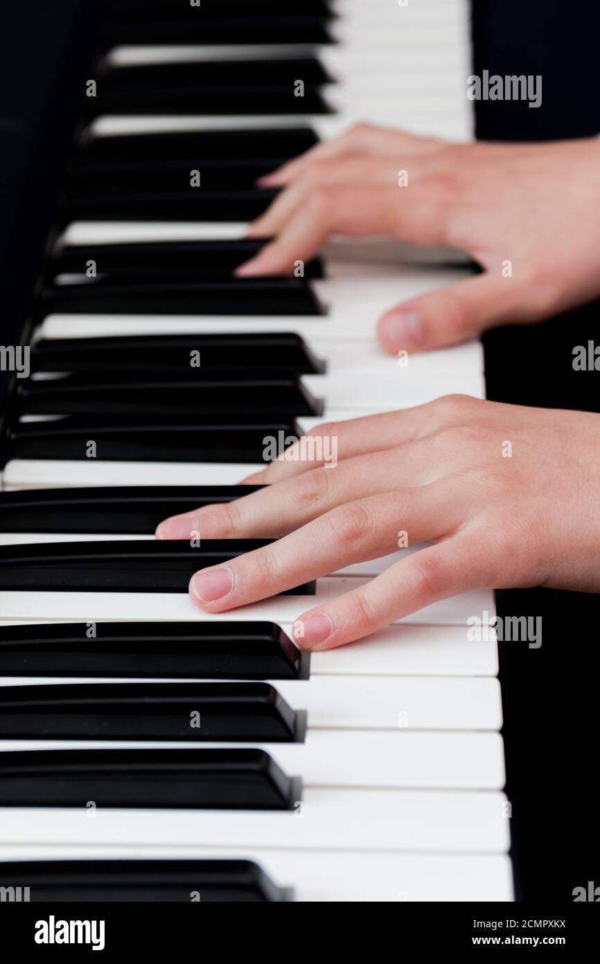 una studentessa in una camicia bianca gioca i tasti di un sintetizzatore. fuoco selettivo. Foto Stock