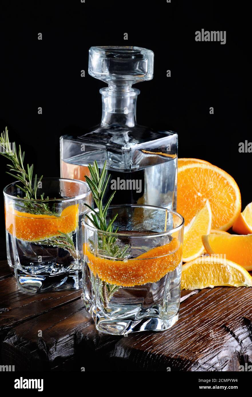 Cocktail classico Dry Gin con tonico e scorza d'arancia con un rametto di rosmarino su una tavola di legno con Foto Stock