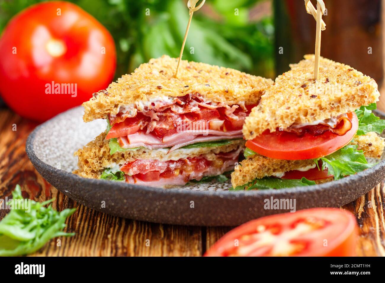 Deliziosi panini con insalata verde, prosciutto, pancetta, pomodori freschi e salsa. Concetto di pranzo. Messa a fuoco selettiva Foto Stock