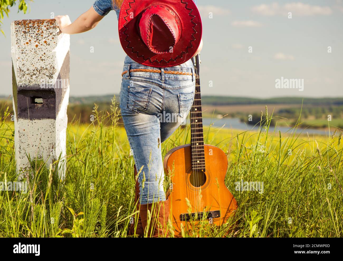 donna che suona la chitarra su sfondo prato primaverile Foto Stock