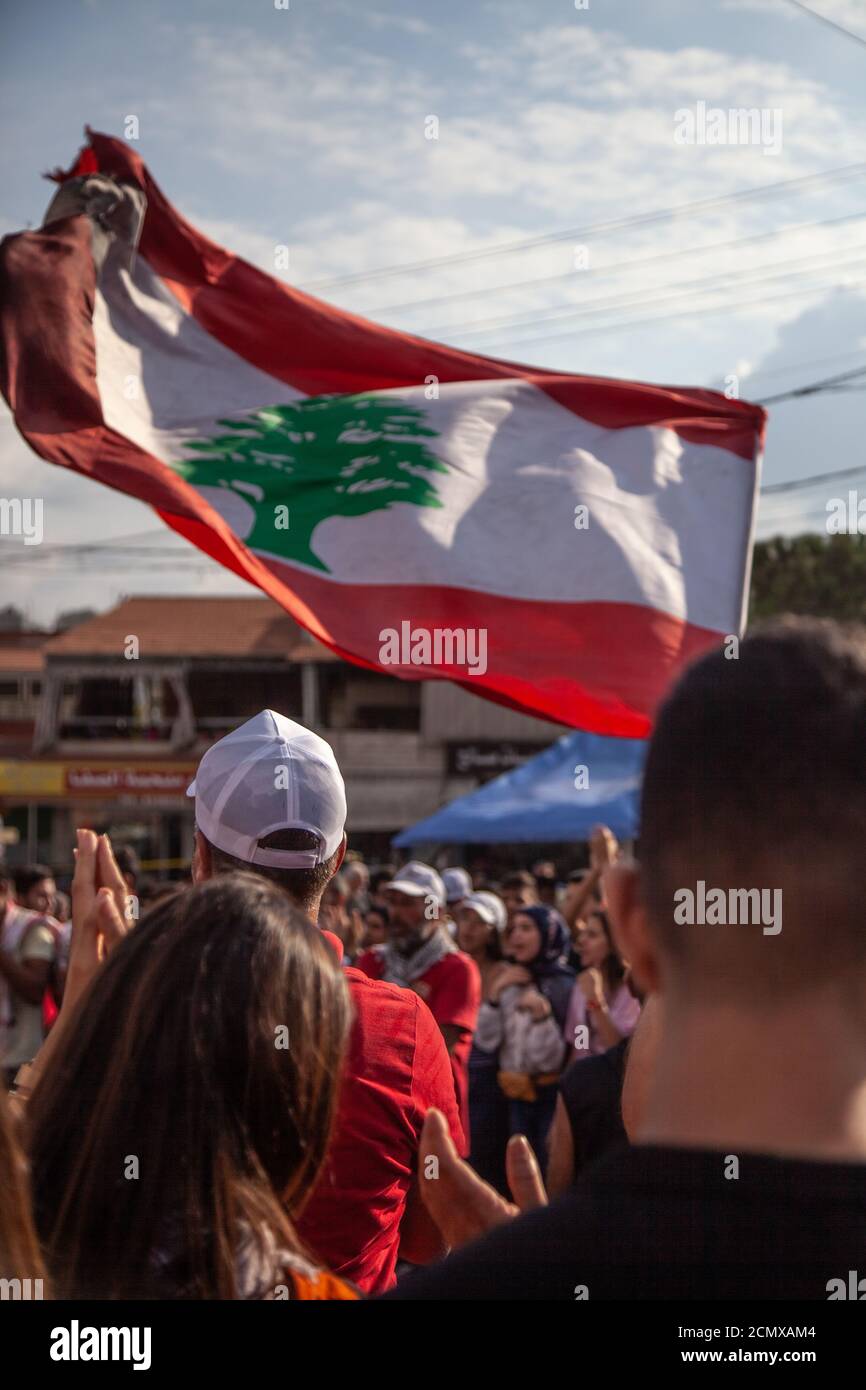 Manifestanti libanesi che innalzano la Bandiera del Libano nel cielo al Rivoluzione contro il governo Foto Stock