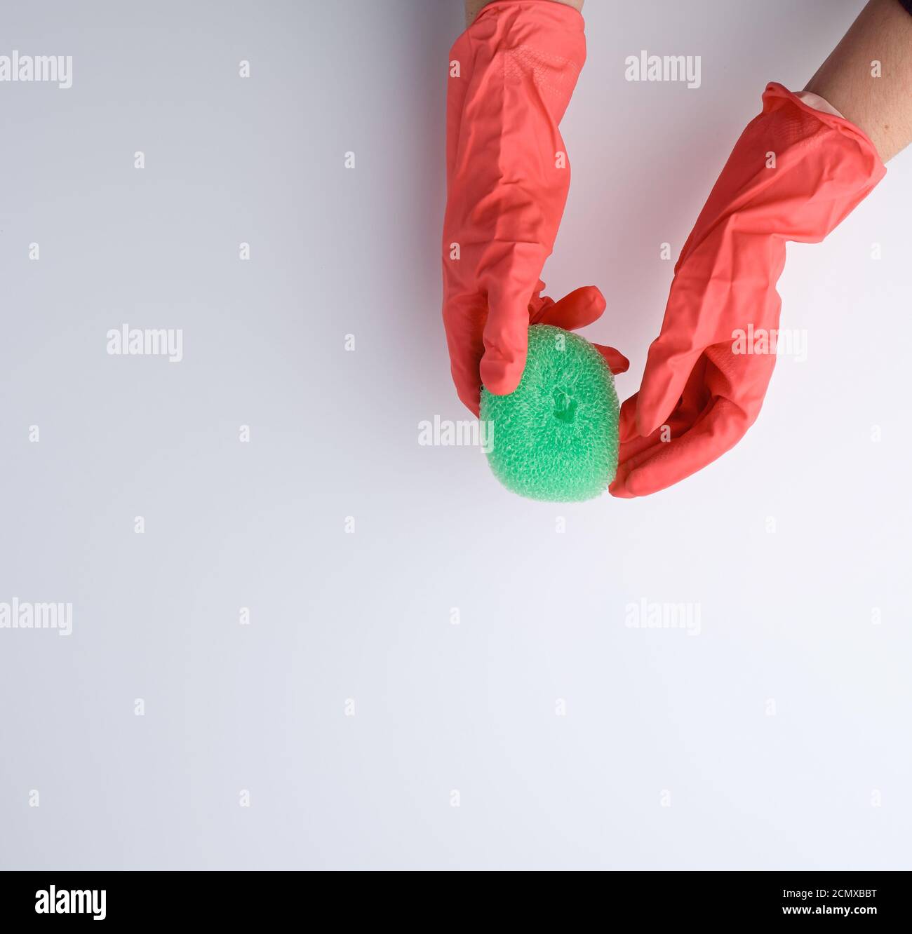 la mano in un guanto arancione contiene una spugna da cucina Foto Stock