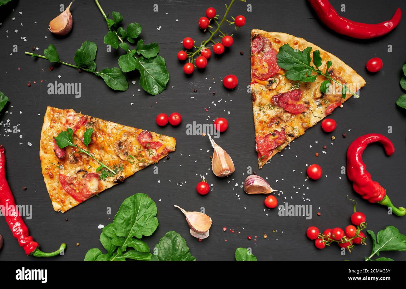 pezzo triangolare di pizza cotta con funghi, salsicce affumicate, pomodori e formaggio Foto Stock