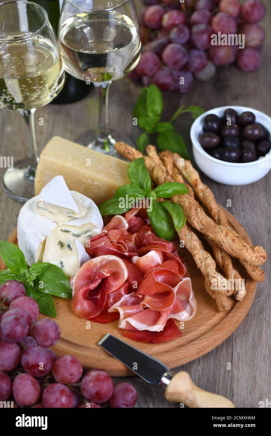 Antipasto. Spuntini a base di vino di prosciutto secco, formaggio camembert con muffa, parmigiano con grissini, olive Foto Stock