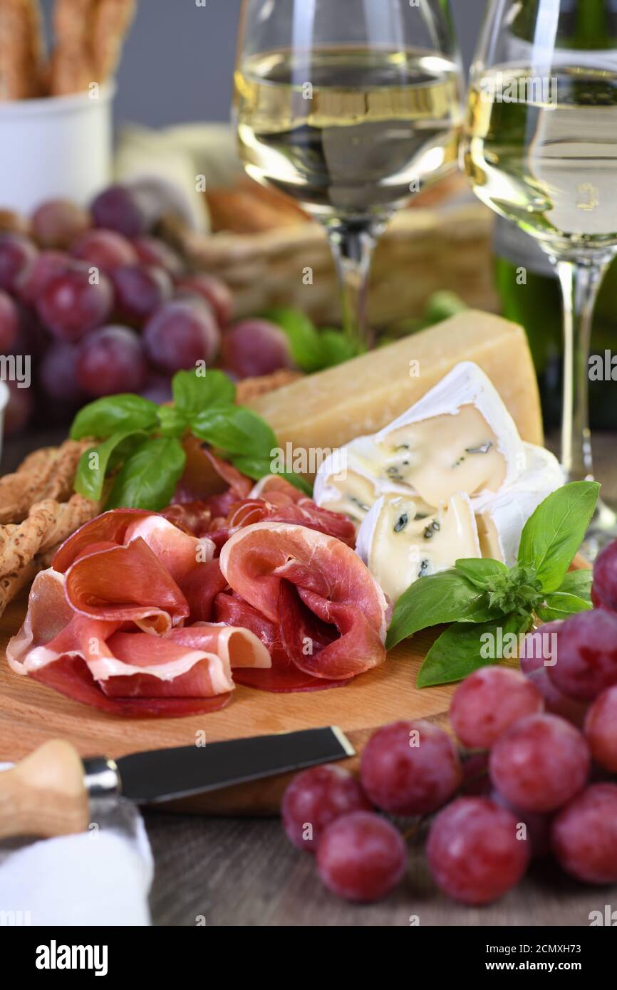Antipasto. Spuntini a base di vino di prosciutto secco, formaggio camembert con muffa, parmigiano con grissini, olive Foto Stock