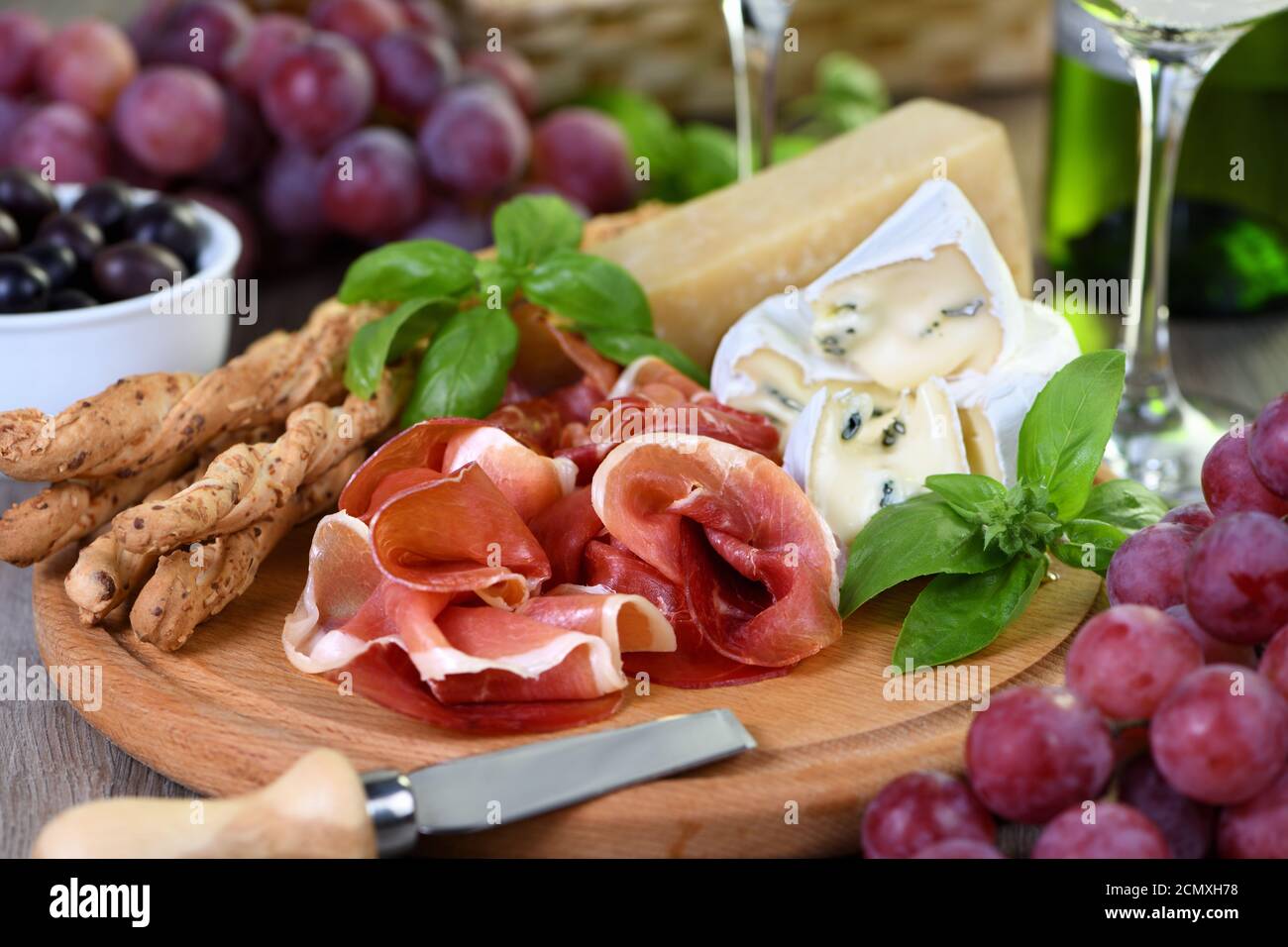 Antipasto. Spuntini a base di vino di prosciutto secco, formaggio camembert con muffa, parmigiano con grissini, olive Foto Stock