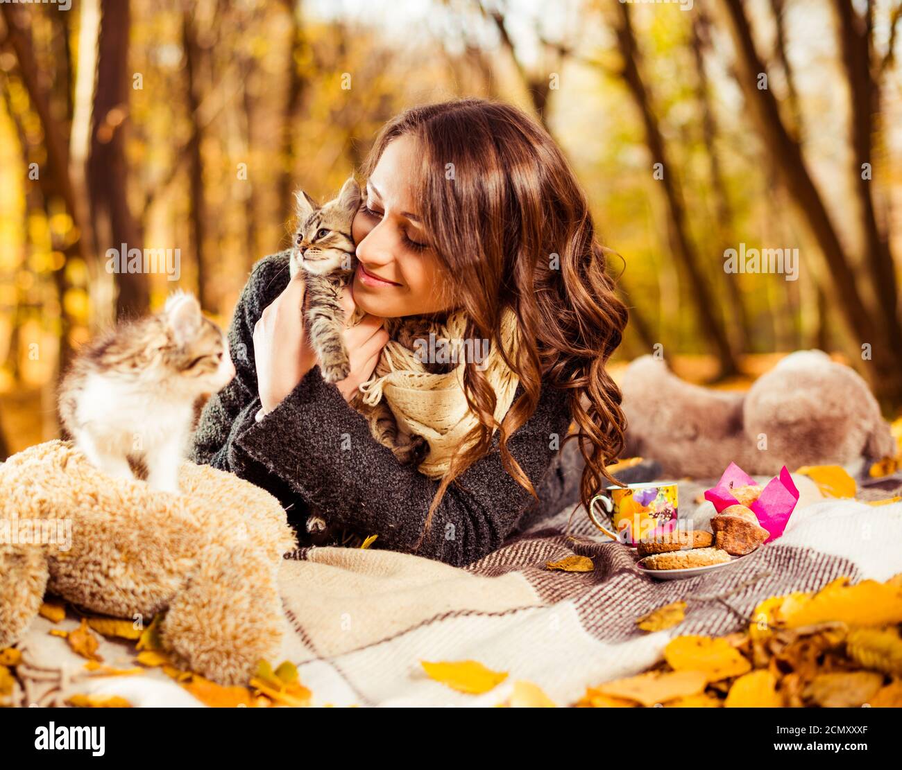 signora con libro e due piccoli gatti giocosi in autunno foresta Foto Stock