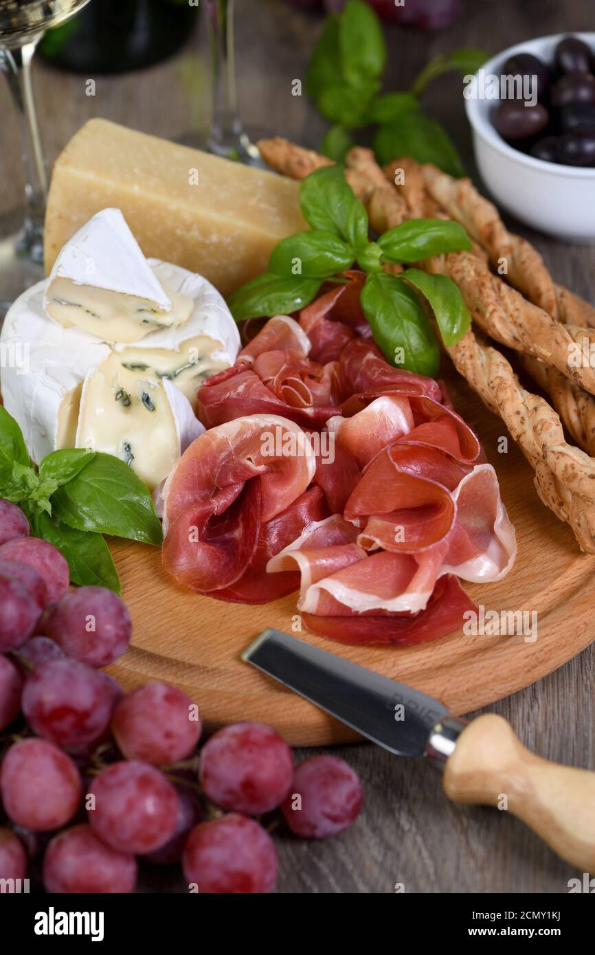 Antipasto. Spuntini a base di vino al prosciutto, formaggio brie con muffa, parmigiano con grissini, olive e p. Foto Stock