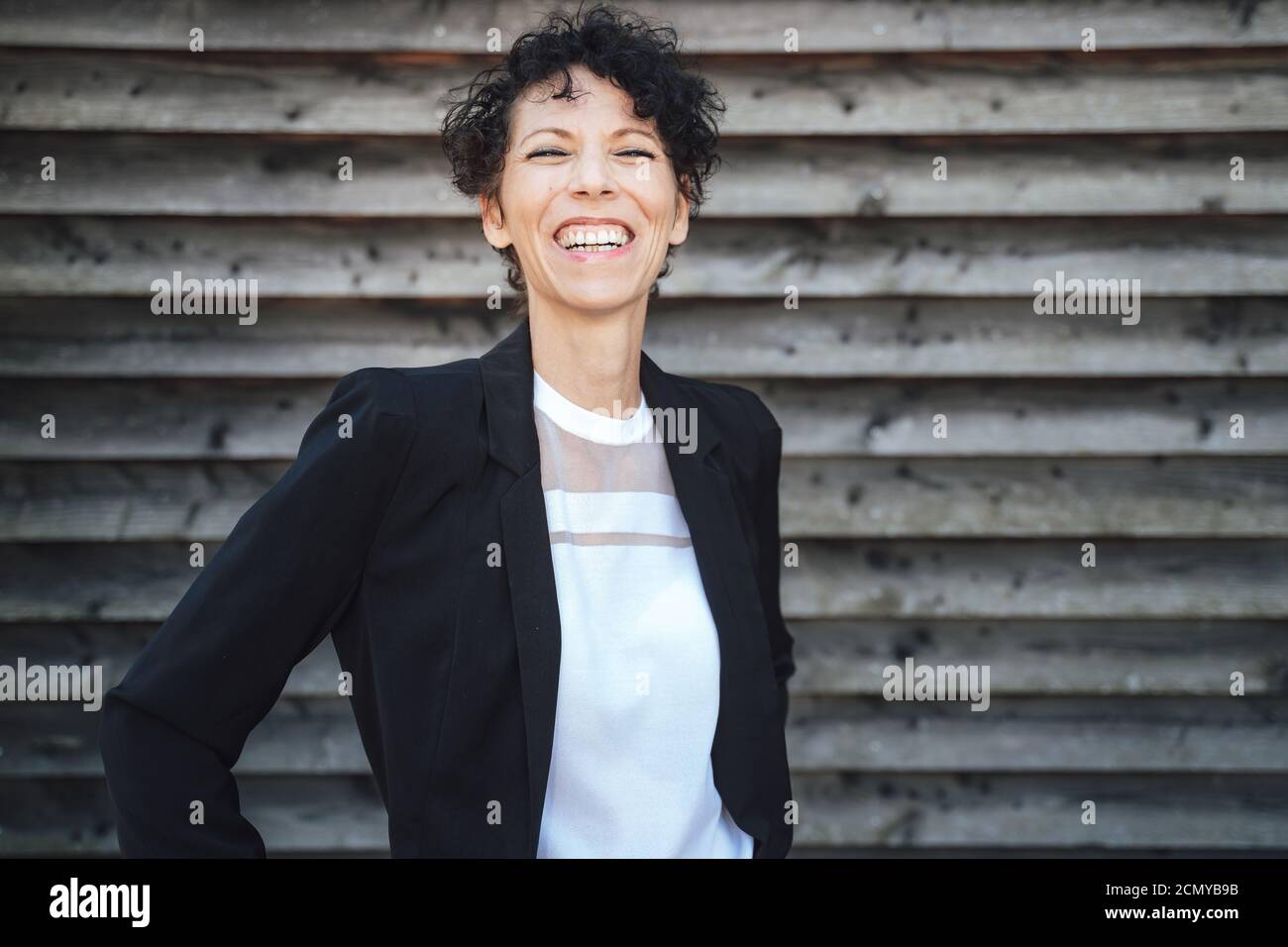Ritratto di allegra imprenditore femminile che indossa la tuta mentre si sta in piedi contro parete Foto Stock