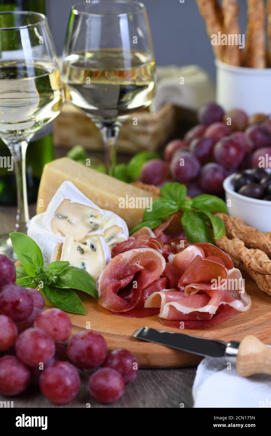 Antipasto. Spuntini a base di vino di prosciutto secco, formaggio camembert con muffa, parmigiano con grissini, olive Foto Stock