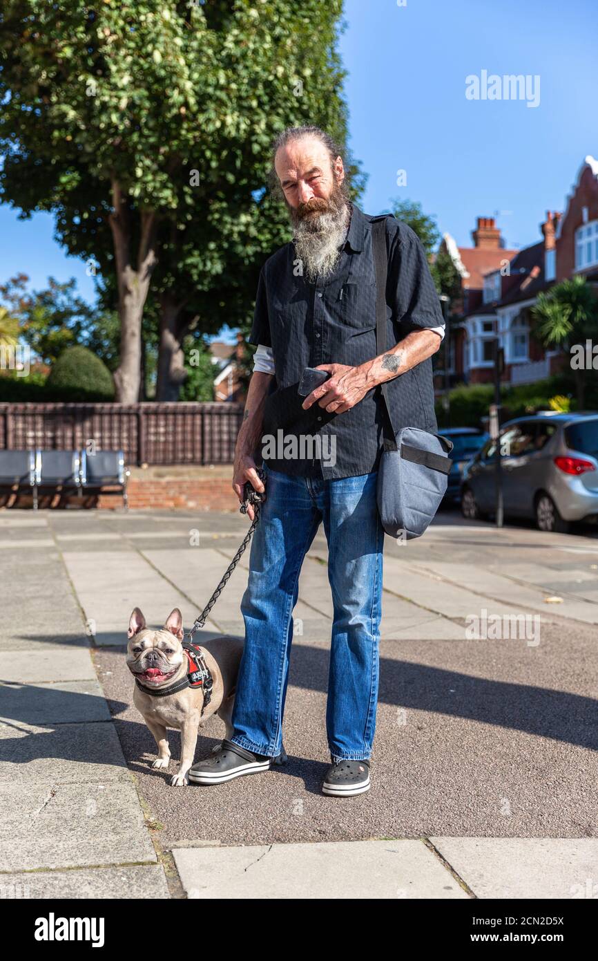 Ritratto a lunghezza intera di un uomo portatore e del suo cane da compagnia, West End Road, West Hampstead, Londra, Inghilterra, Regno Unito. Foto Stock