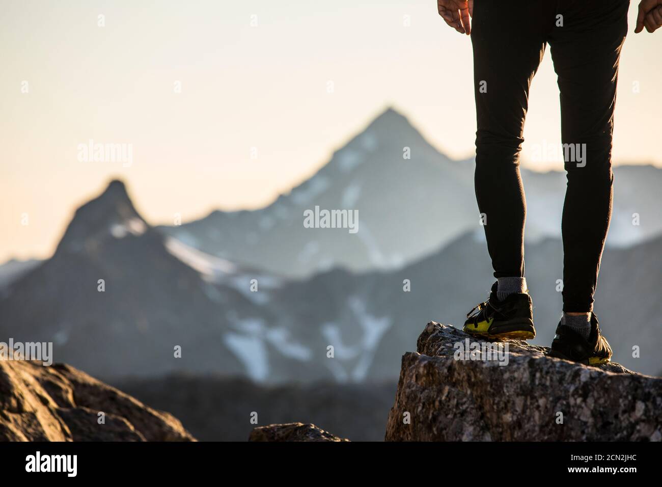 Vista delle gambe e delle scarpe dei corridori arroccati su una cima di montagna. Foto Stock
