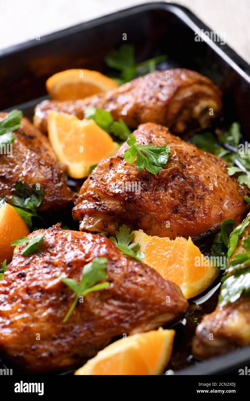 fette appetitose di pollo al forno con crosta fritta croccante e arance in una teglia Foto Stock