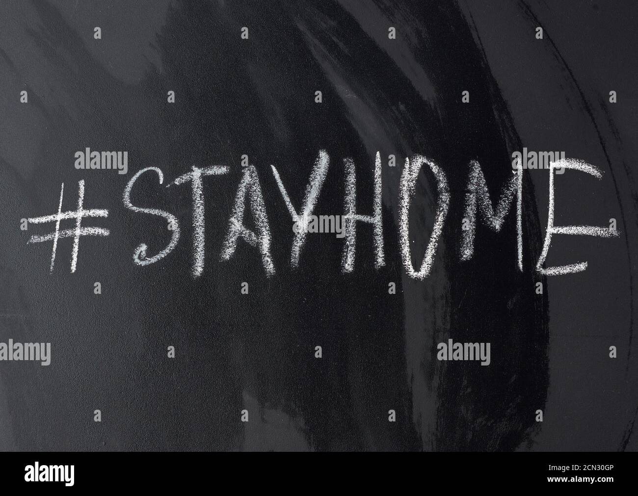 iscrizione rimanere a casa in gesso con un hashtag su un lavagna nera in gesso Foto Stock