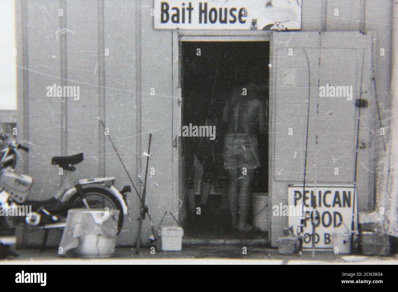 Bella fotografia in bianco e nero degli anni '70 di un uomo che cammina in un negozio di esche. Foto Stock