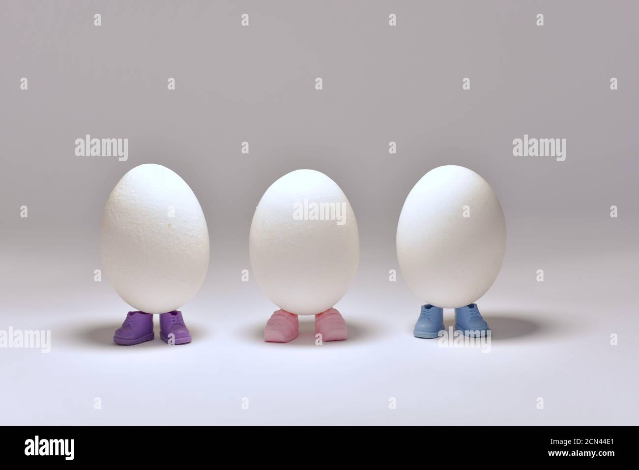 Tre uova sono avvolte in scarpe multicolore, in piedi al centro. Foto Stock