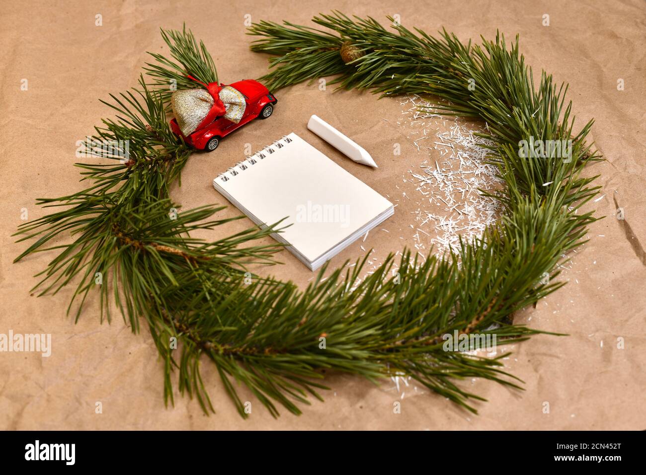 Una corona di rami di pino con una macchina da scrivere rossa con un sacchetto di regali, intorno ad un taccuino con una matita al centro. Foto Stock