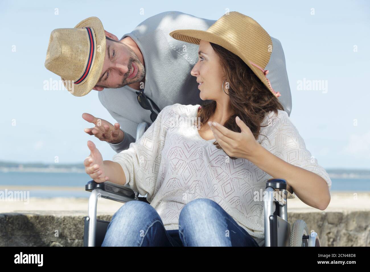 coppia in discussione sulla donna lungomare in sedia a rotelle Foto Stock