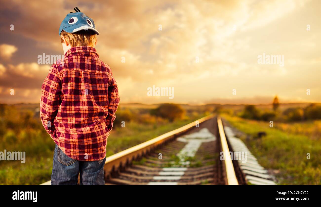 Carino ragazzo in cappello in piedi in campagna paesaggio ferroviario Foto Stock