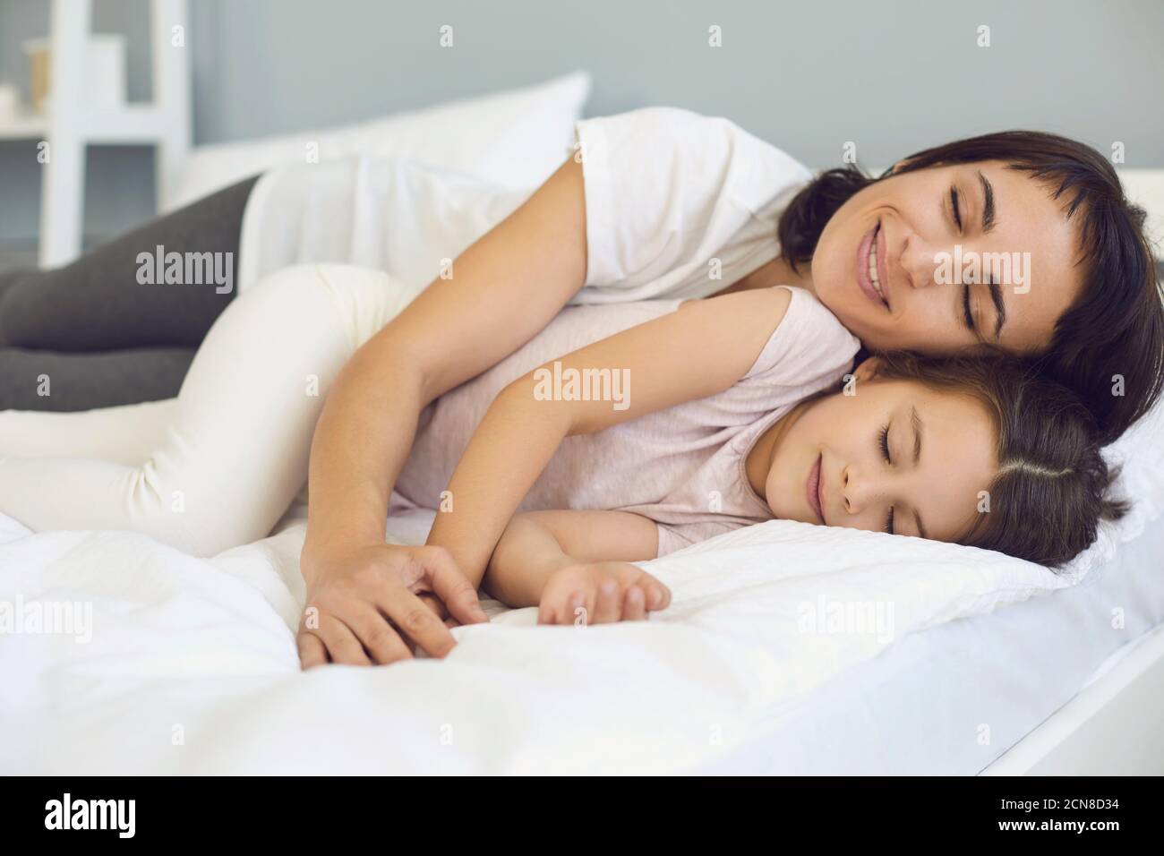 Madre e figlia felici e rilassati che si coccolano sul letto morbido camera tranquilla durante il fine settimana Foto Stock