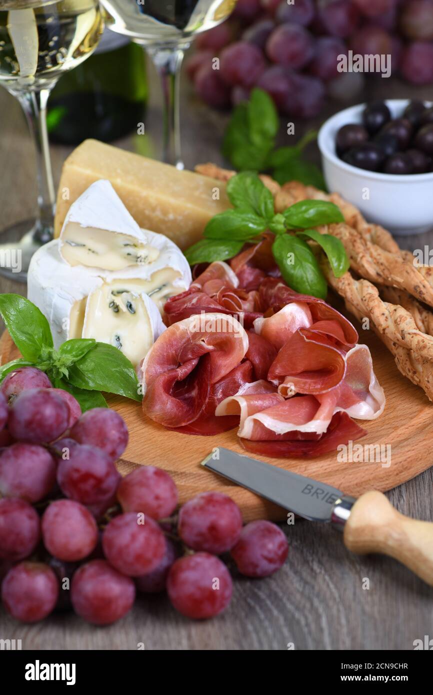 Antipasto. Spuntini a base di vino al prosciutto, formaggio brie con muffa, parmigiano con grissini, olive e p. Foto Stock