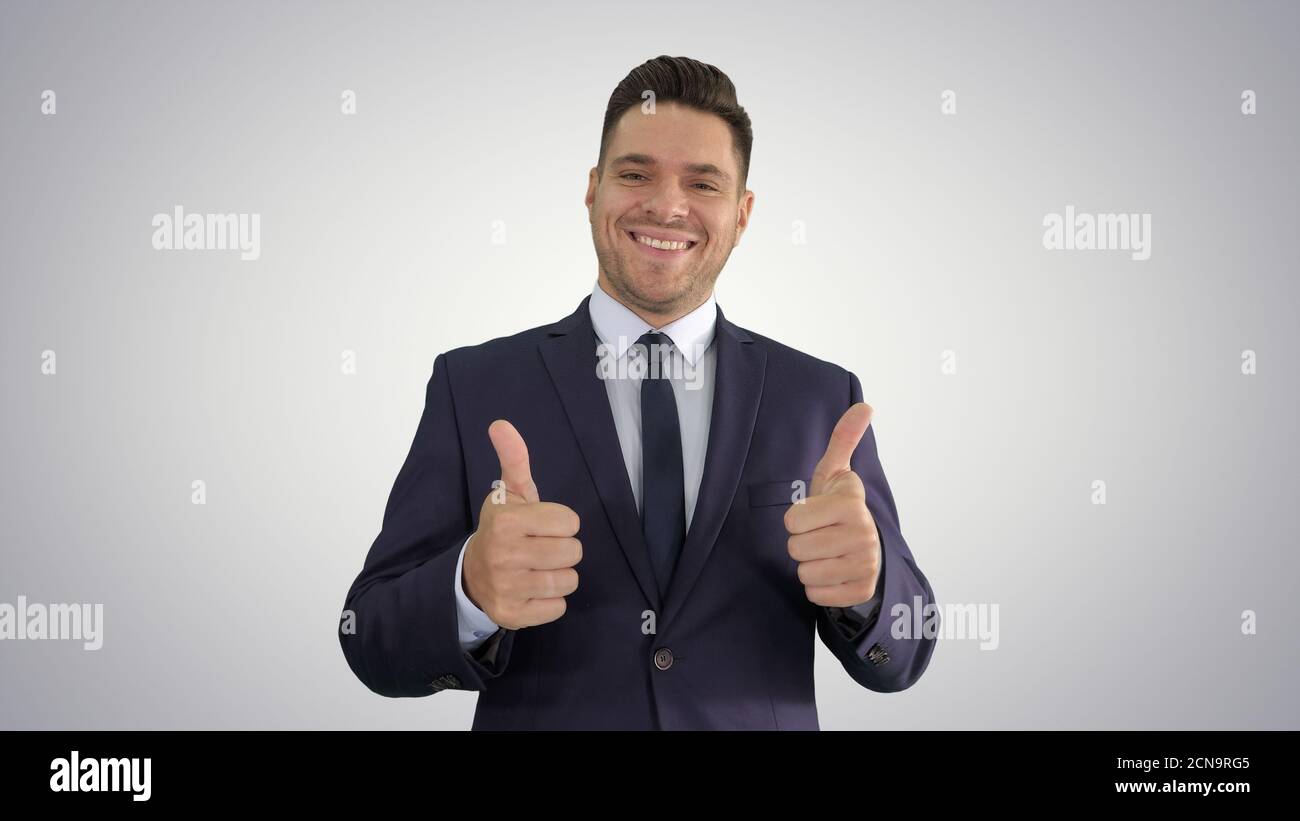 Uomo d'affari felice che tiene i pollici su sfondo gradiente. Foto Stock