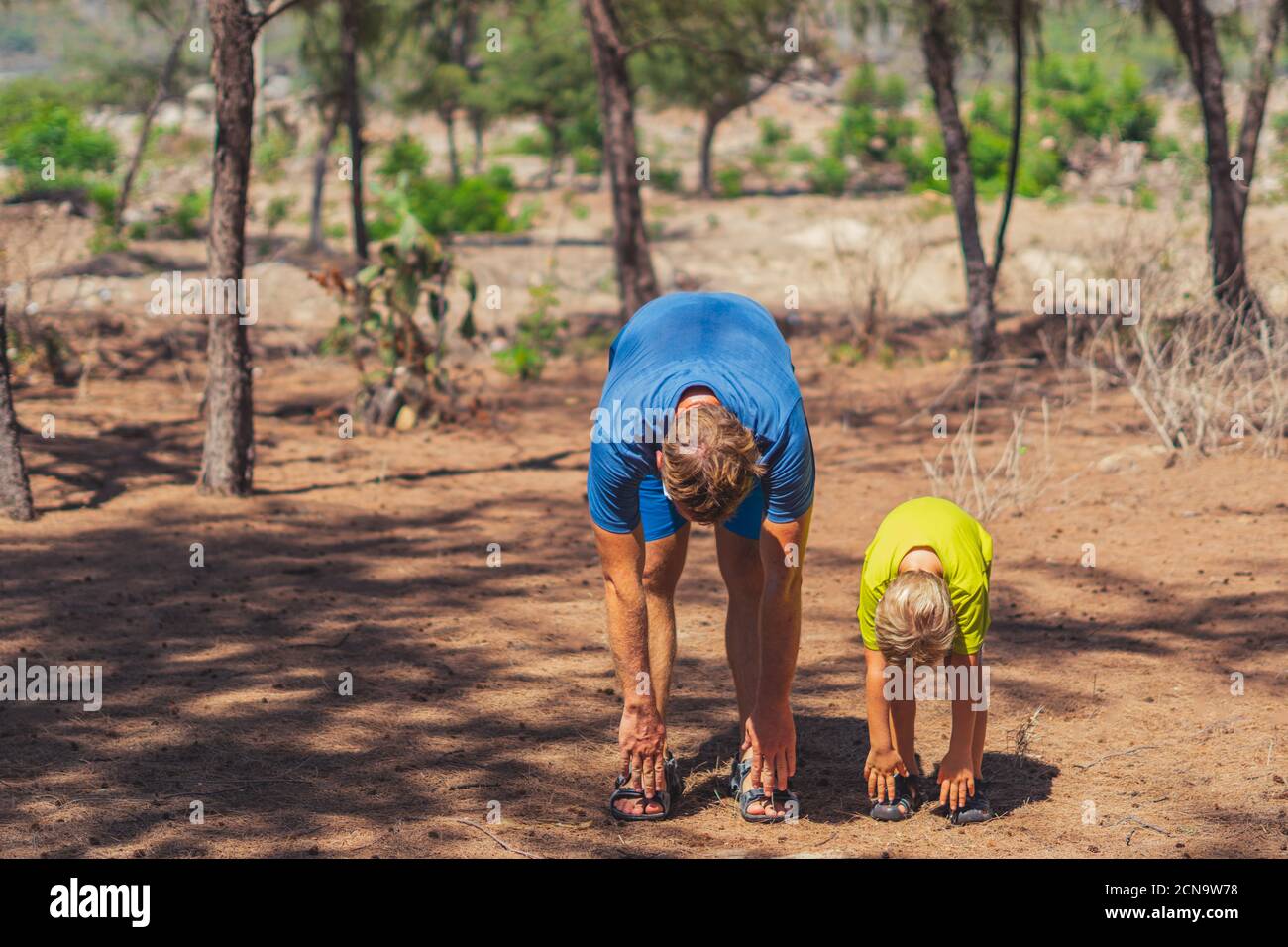 Sport padre figlio che si esercita in foresta parco aria fresca, allenamento godendo insieme, squatting e tecnica di curva laterale, passeggiata natura sole giorno. Papà Foto Stock