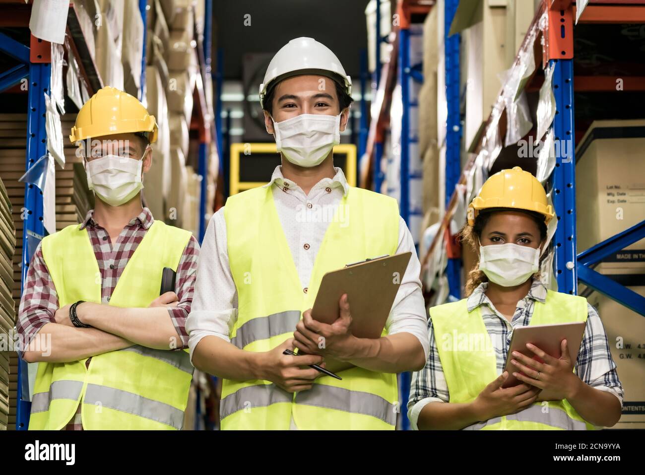 Team di lavoro magazzino interracial con maschera facciale Foto Stock