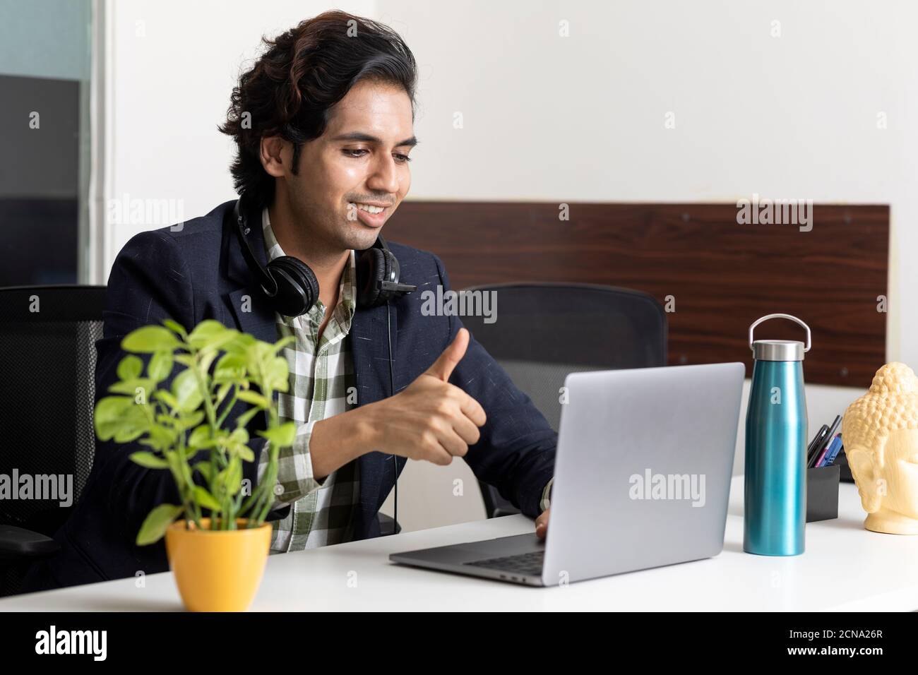 Ritratto di un giovane uomo d'affari indiano che lavora dal suo laptop nella sua cabina d'ufficio, ambiente aziendale, dipendente del call center, videoconferenza. Foto Stock