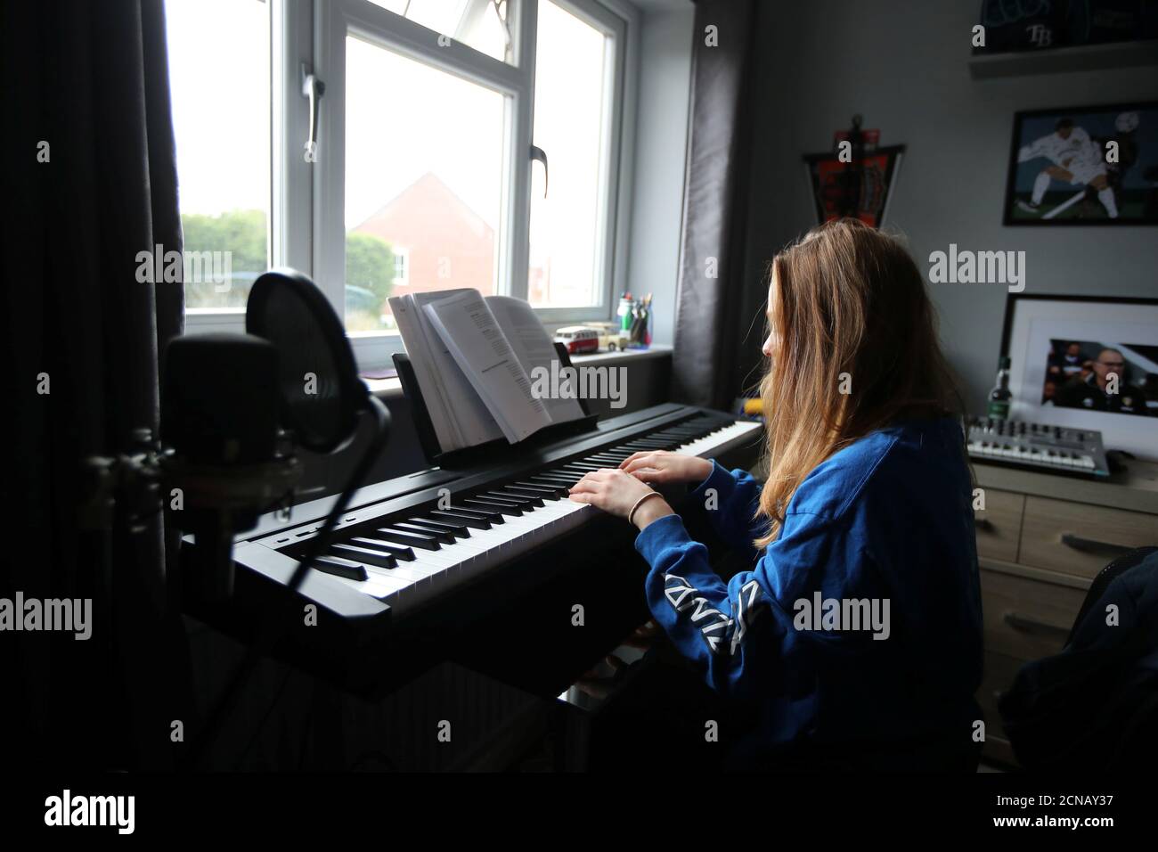 Clara prova sul suo pianoforte da tastiera per una valutazione di  performance virtuale mentre studia per una laurea di musica commerciale  come continua la diffusione della malattia del coronavirus (COVID-19),  Davenham, Gran