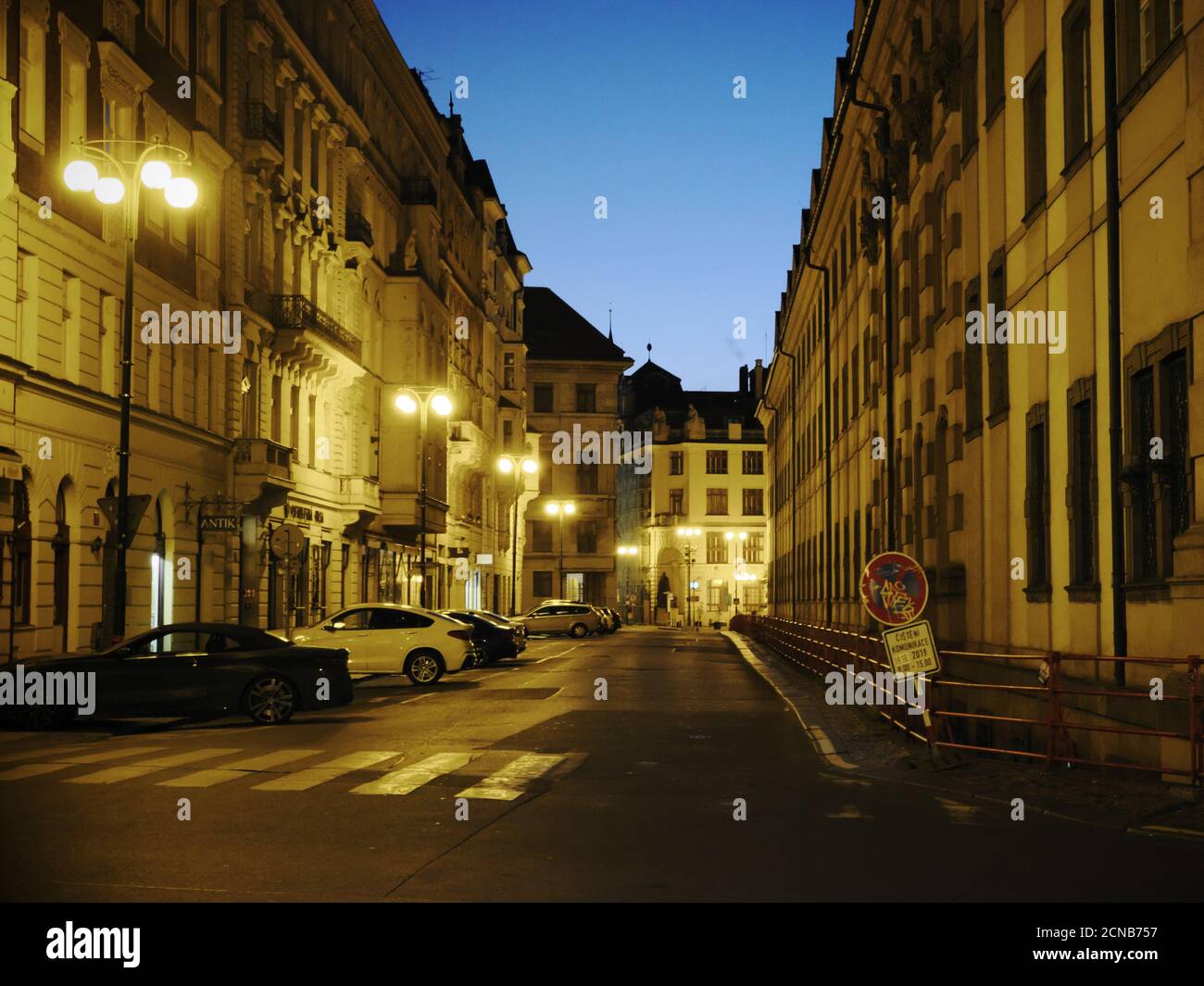 Praga, Repubblica Ceca, 13 ottobre 2019. Auto moderne parcheggiate lungo una vecchia strada europea. Crepuscolo e luce delle lanterne. Foto Stock