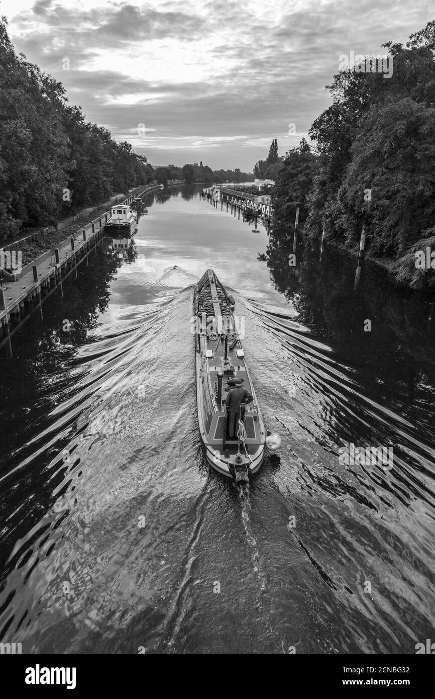 Un mercante di carburante diesel e solido guida la sua barca sul canale lungo Teddington Lock, Inghilterra, Regno Unito. In bianco e nero. Svegliati in acqua. Foto Stock