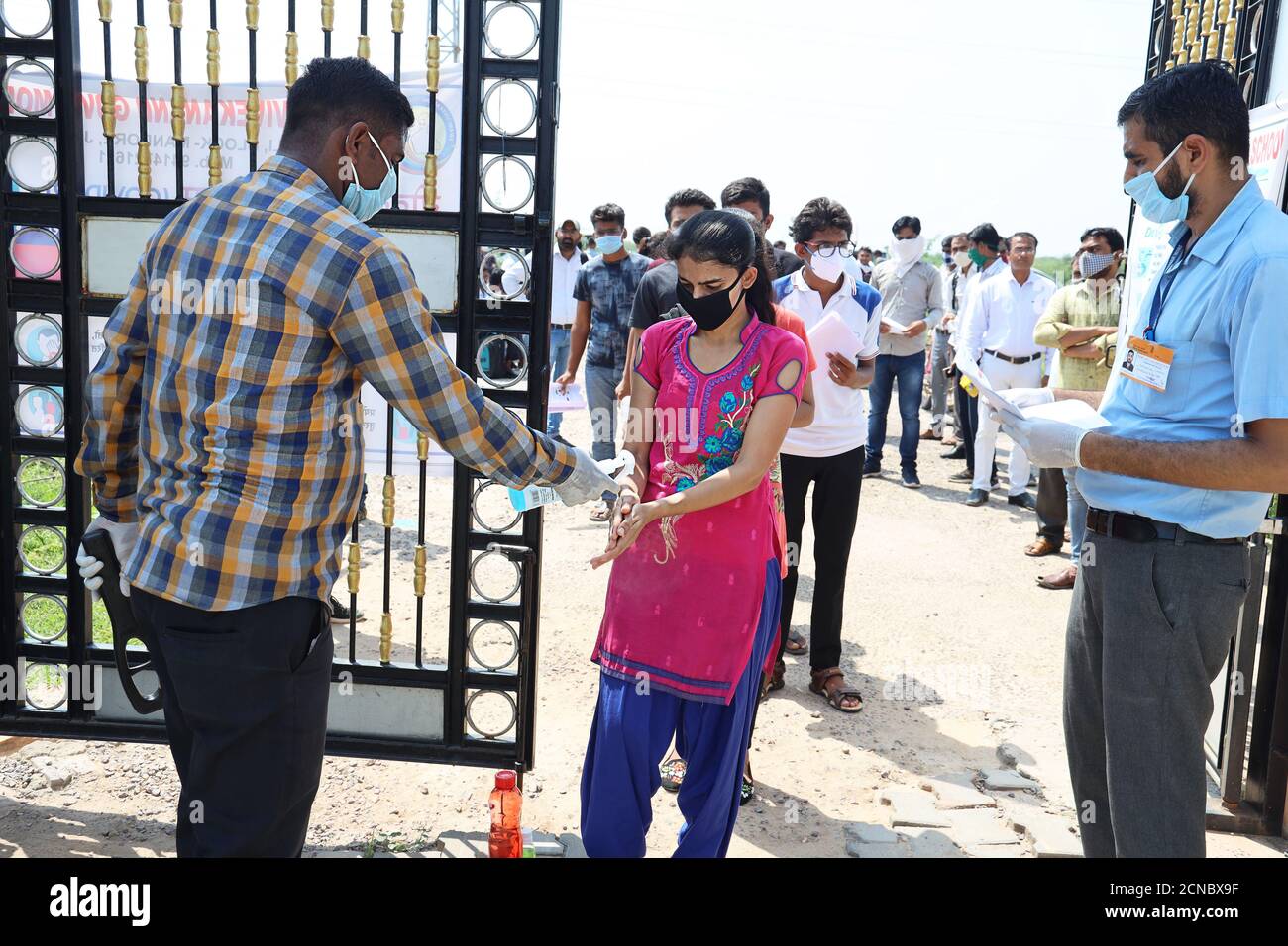 Jodhpur, Rajasthan, India, settembre 13,2020: Persona di sicurezza igienizzante mani di studente prima di entrare nel centro di esame per prevenire la diffusione Foto Stock