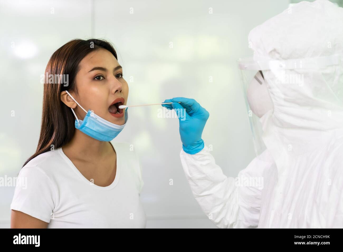 Il personale medico esegue test COVID-19 con tampone alla gola a casa Foto Stock