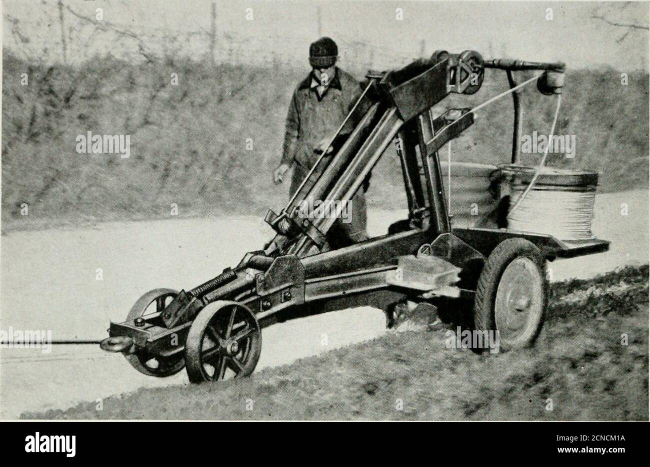 . Rivista Bell Telephone . Le tratte medie da 350 a 450 piedi, utilizzando un filo di acciaio ad alta resistenza, riducono materialmente i costi di costruzione le correnti di portante telefonica, essendo di frequenze molto alte, possono passare sulla linea di alimentazione simultaneamente con le correnti di potenza, senza alcuna interferenza mutual  LW AT  , mentre ciò potrebbe non essere fatto se si utilizzassero correnti telefoniche ordinarie. 120 Bell Telefono Magazine INVERNO. Un tale aratro, tirato da un camion, seppellisce un filo telefonico isolato in gomma nel terreno in un'unica operazione economica per realizzare tutto questo, l'equipaggiamento presso i locali degli abbonati verosimilmente appaiono Foto Stock