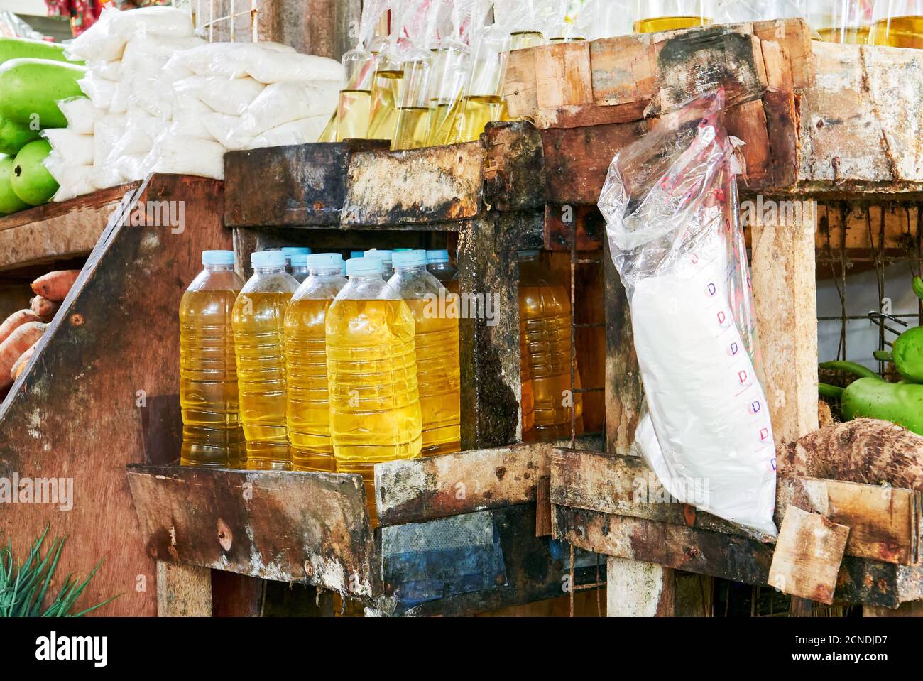 Vista ravvicinata di olio vegetale, sale e verdure imbottigliati in plastica da vendere su uno scaffale molto sporco in una bancarella di mercato nelle Filippine, in Asia Foto Stock