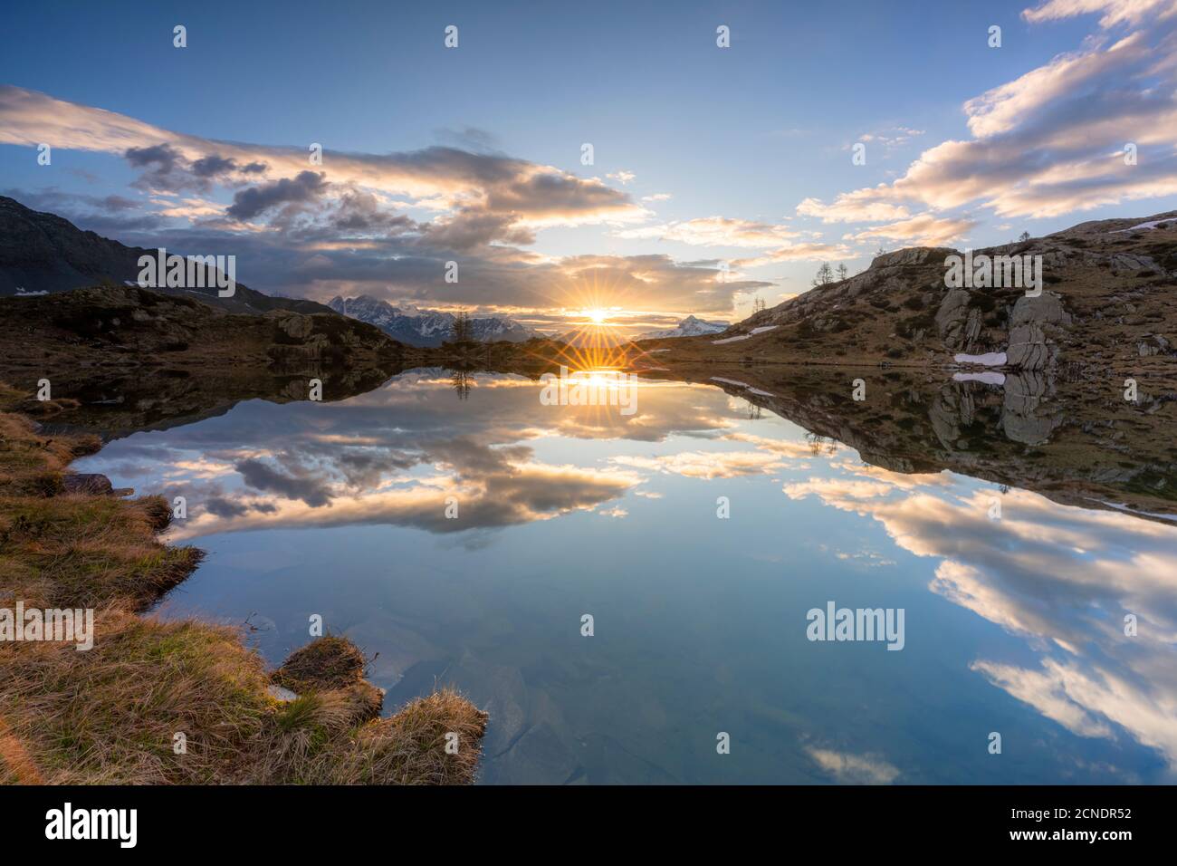 Sunburst sulle acque limpide del lago Zana durante l'alba, Valmalenco, provincia di Sondrio, Valtellina, Lombardia, Italia, Europa Foto Stock
