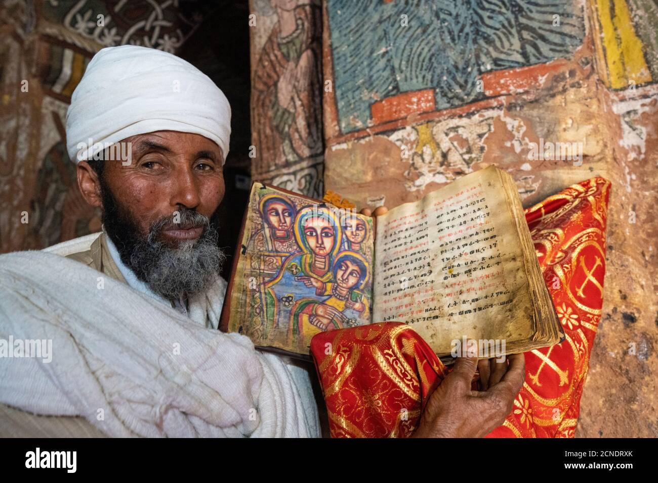Sacerdote ortodosso che detiene una vecchia Bibbia con santi dipinti a mano, Abuna Yemata Guh chiesa, Gheralta Montagne, Tigray Regione, Etiopia, Africa Foto Stock