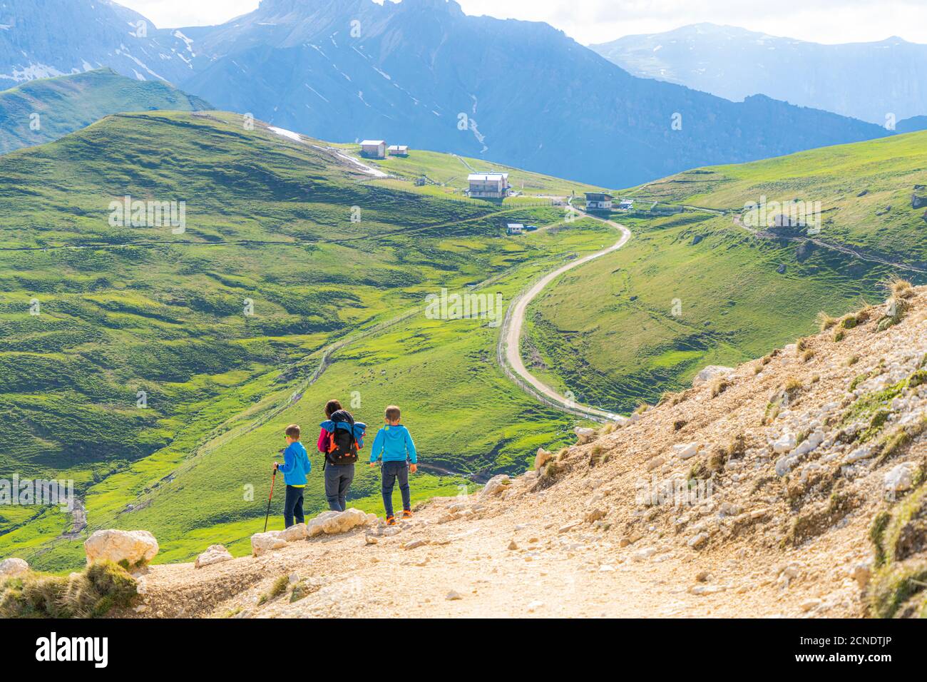 Madre con due figlioli che camminano su un sentiero in prati verdi verso il Rifugio Sassopiatto, Dolomiti, Trentino-Alto Adige, Italia, Europa Foto Stock