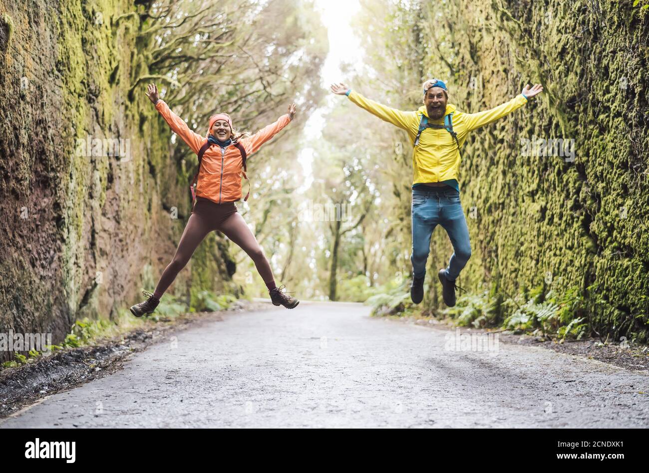 Felice coppia saltando nel parco turistico - giovane turista che ha divertimento facendo escursioni nella foresta selvaggia Foto Stock