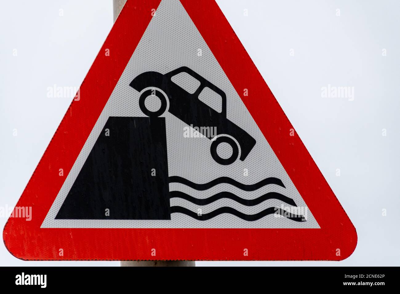 Una vista ravvicinata di un cartello stradale del Regno Unito che segnala un bordo non protetto con una forte caduta in acqua, che si trova normalmente nei porti e sulla costa. Foto Stock